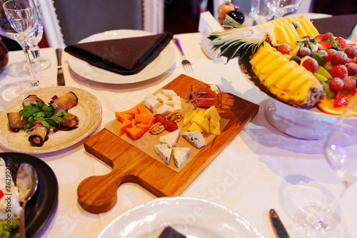 Served banquet table. Wooden board with cheese platter in the center.