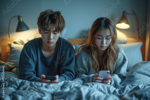 Asian young phone addict couple don't pay attention with each other. Family problem, New marriage man and woman partner lying down on bed, using smartphone, ignore husband and wife in bedroom at home.