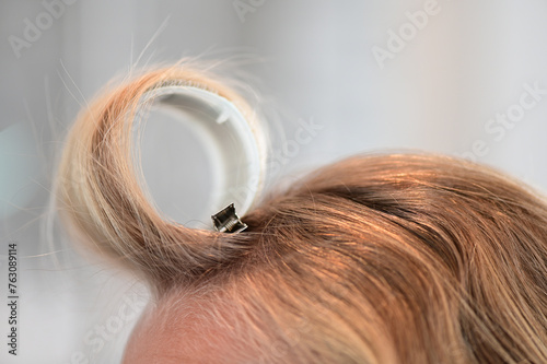 Close up of a hair roller to create bangs or curly hair on a blonde woman