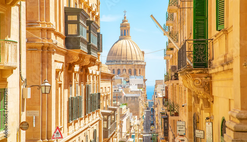 Sunny street in Valletta old town, St Paul’s Anglican Pro-Cathedral on a background