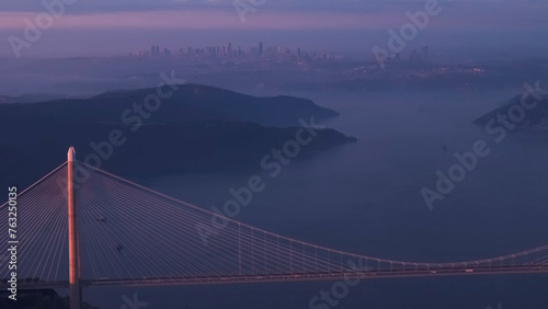 Aerial view of vehicles passing over Istanbul Yavuz Sultan Selim Bridge in sunrise light ships passing under it to enter the Bosphorus and its surroundings