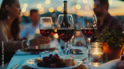 Happy people drinking red wine sitting at restaurant table - Young people of various nationalities enjoying dinner on rooftop together - Food and drink concept with man and woman having dinner