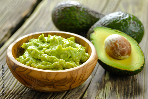 Halved avocado and guacamole in wooden bowl for healthy food concepts.