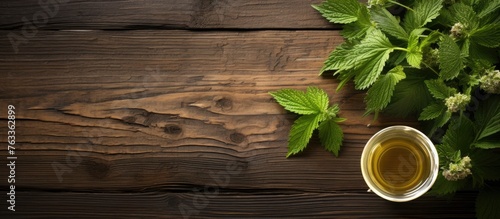 A cup of nettle tea next to a plant on a wooden table