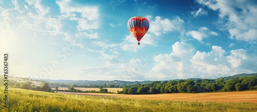 A red and blue hot air balloon soaring above a meadow
