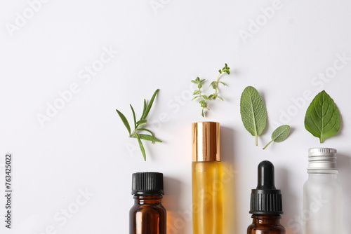 Cosmetic bottles with herbs on a white background