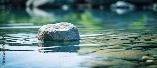 Rock in water reflecting surrounding stones