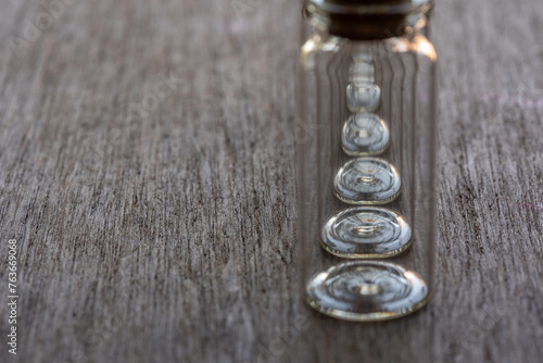 hilera de frascos de vidrio enfocando en la base circular, sobre mesa de madera con espacio para texto, 