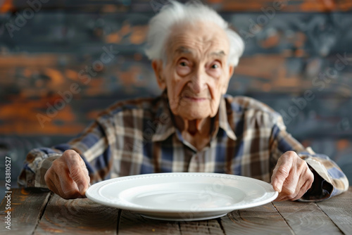 Old person in front of an empty plate , elders poverty and undernutrition concept image with a mature person with nutritional deficiencies