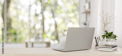 A back view image of a laptop on a wooden desk in a minimalist bright living room.
