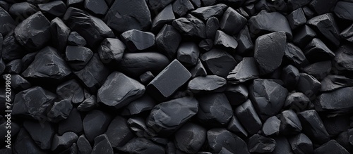 A close-up view of a heap of black rocks against a dark background