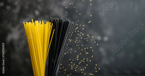 Contrast of yellow and black spaghetti strands. Bunch of yellow and black spaghetti against dark blurred background. Yellow spaghetti and squid ink pasta close up