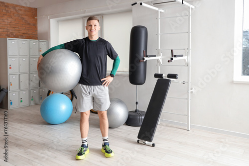 Sporty young man with fitball at gym