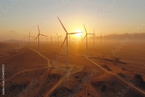 Golden sunset over a vast desert wind farm with towering turbines silhouetted against the dusky sky.