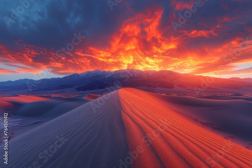 A dramatic desert sunset with a blazing sky over sand dunes.