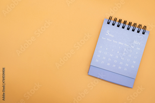 Blue desk calendar for MAY 2024 isolated on orange background. Calendar concept with copy space. Flat lay.