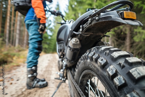 rider standing next to a bike, focus on dual sport tire tread