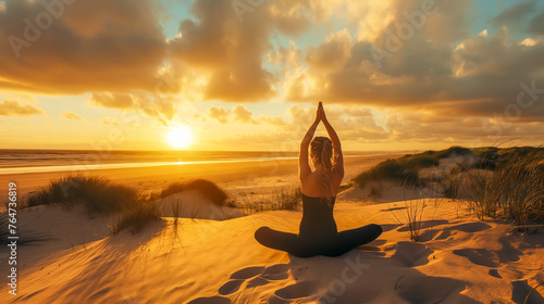 A woman is sitting on the beach, practicing yoga