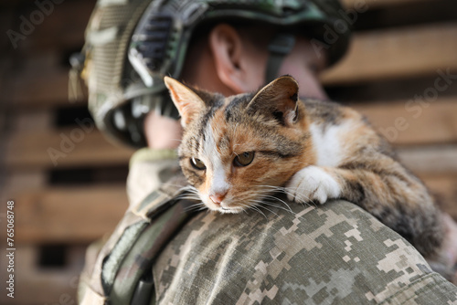 Ukrainian soldier with little stray cat outdoors, closeup