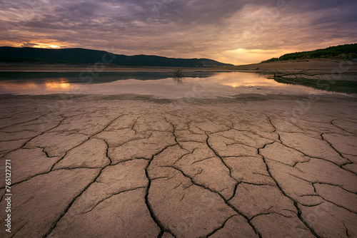 Sunset at the Yesa reservoir, Navarra, during a time of severe drought with the ground cracked by the sun and the lack of water