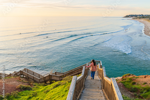 Woman descends the South Port Beach stairs captivated by the spectacular sea view during sunset, Port Noarlunga, South Australia