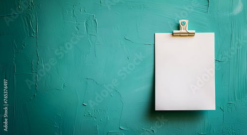 A blank sheet of white note paper for writing messages on a green wall.