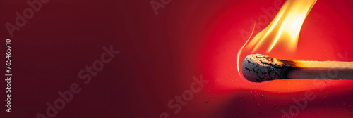 Burning match with a bright flame on a red background. Concept: Fire danger, Idea and inspiration, fire safety. Banner with copy space