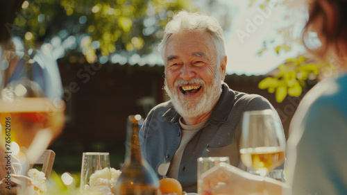 Elderly man laughing joyfully, sharing genuine happiness at an outdoor family gathering.
