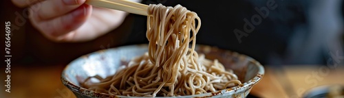 Action shot of soba noodles being lifted from a bowl with chopsticks emphasizing the texture and heartiness of the dish