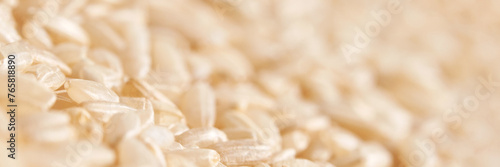 A background of dry brown rice grains showcases the integral, uncooked basmati texture. The macro view highlights the raw nature of this organic, whole food. Horizontal banner