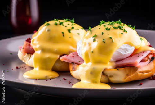 Ham eggs benedict on a white plate with hollandaise sauce, styled with yellow and magenta.
