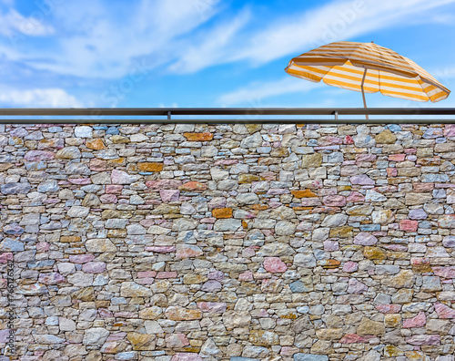 Parasol de plage derrière mur de pierres