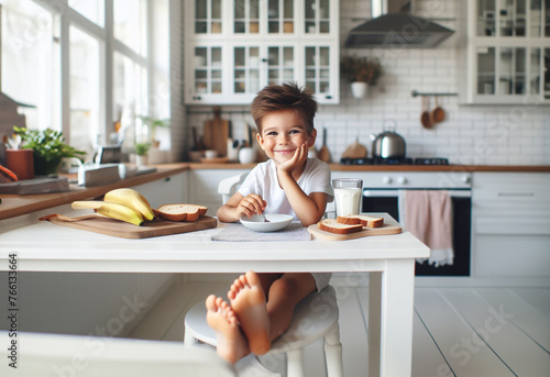 Junge Kind Heranwachsender sitzt fröhlich glücklich lächelnd barfuß am Tisch Frühstück zu Hause in hell Ausstattung Kindheit Ernährung Genuß Freude, Start in den Tag, Küche lebensstil frühstücken