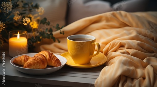 A cozy still life of a cup of coffee, croissants, and a candle