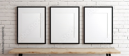 Three empty picture frames are placed on a rustic wooden bench situated against a textured brick wall