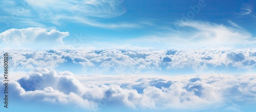 A scenic view capturing a commercial plane flying in the clear blue sky filled with fluffy white clouds