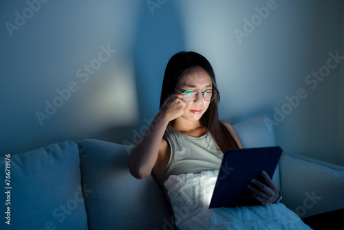 Woman rubs her eyes after using glasses look at the tablet computer at home