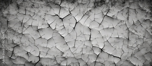 Capture of a black and white image featuring a wall with prominent cracks and fractures running through it