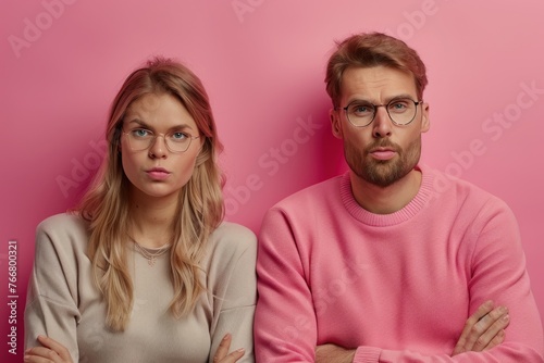 Couple with folded arms looking at the camera with serious expressions on their faces