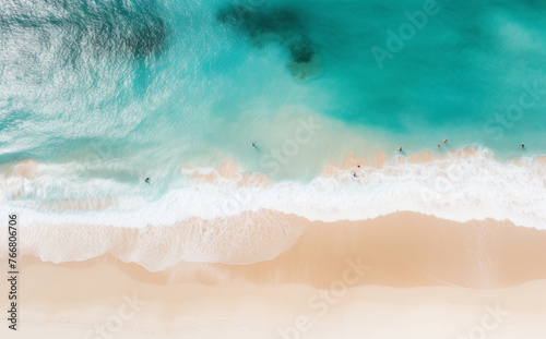 Overhead shot of a beach as people swim in the water, enjoying a sunny day by the sea