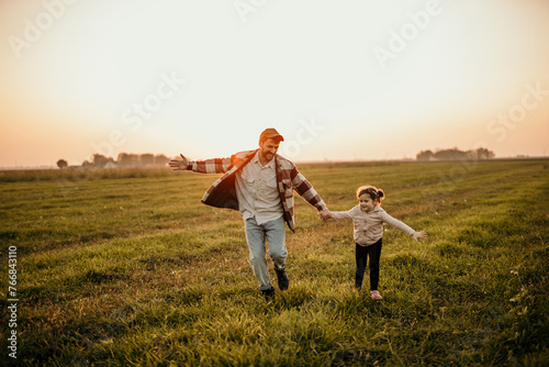 Father and daughter bonding in a picturesque countryside setting as the sun sets behind them