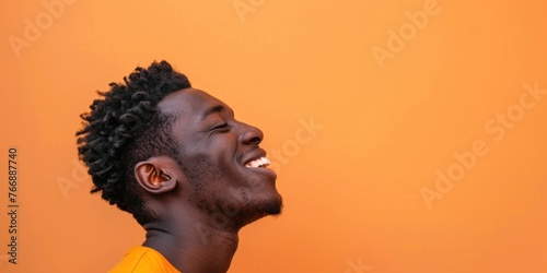 Joyful African Man Laughing on Orange Background