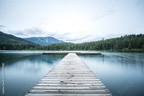 A long wooden pier on a smooth lake. 