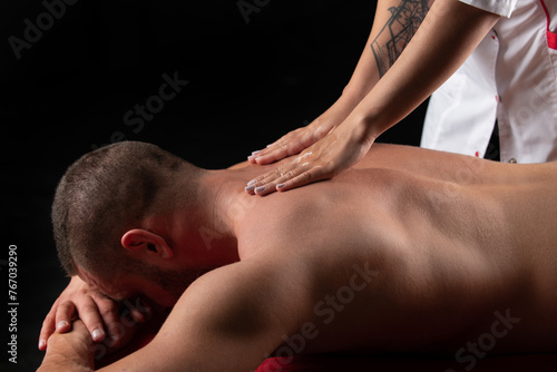 Man back massage from masseur. Massage on the back. Male getting relax massage on spa treatment. Therapist working with shoulders.