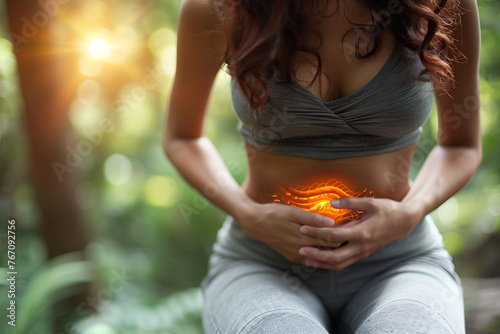 Young woman with burning abdominal pain holding her stomach. 