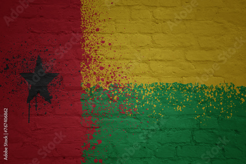 colorful painted big national flag of guinea bissau on a massive brick wall