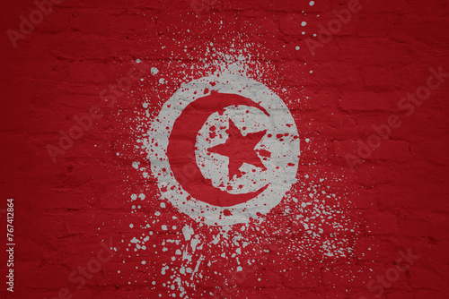 colorful painted big national flag of tunisia on a massive brick wall