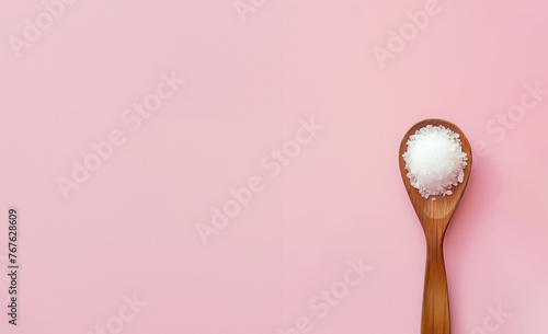 cristaux de sel blanc de Camargue, France dans une cuillère en bois, sel de mer ou sel de roche sur fond rose pastel avec espace négatif copy space