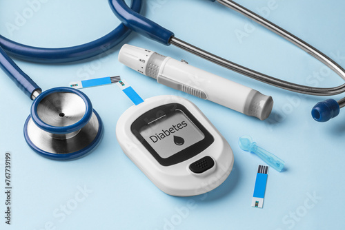 Diabetes concept with blood glucose meter, lancet and stethoscope on blue background