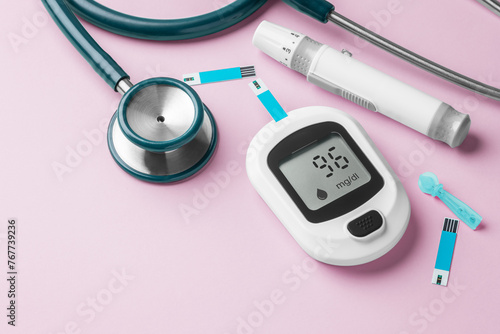 Blood glucose meter, lancet and stethoscope on pink background, diabetes concept